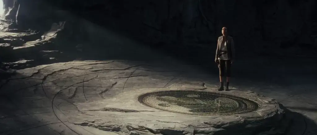 Rey stands next to the prime jedi mosaic on Ahch-To